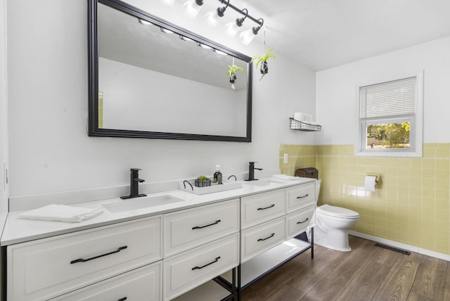 bathroom with tile walls, vanity, wood-type flooring, and toilet