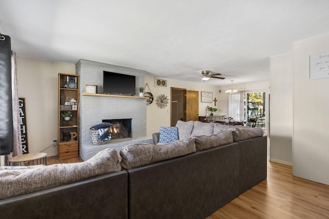 living room featuring light hardwood / wood-style flooring, a brick fireplace, and ceiling fan