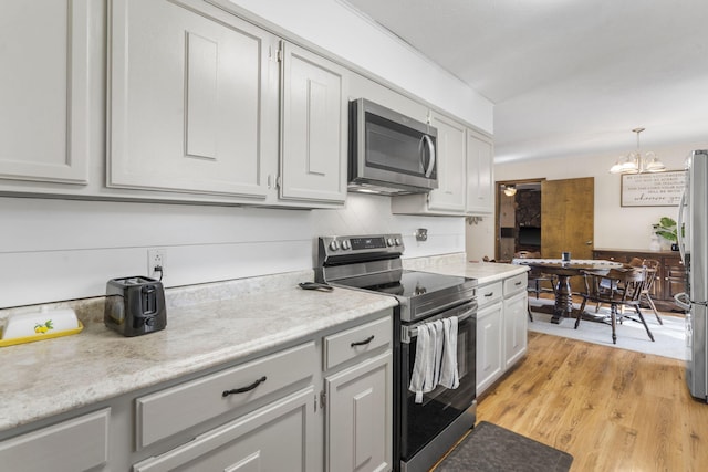 kitchen featuring light hardwood / wood-style floors, stainless steel appliances, an inviting chandelier, and hanging light fixtures