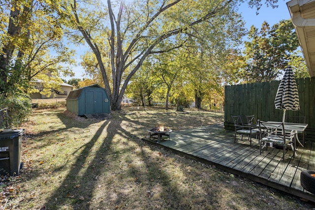 view of yard featuring an outdoor fire pit, a storage shed, and a deck