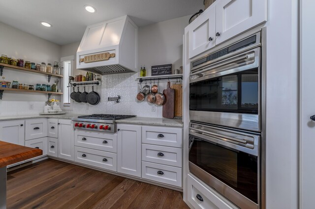 236 N Dade 147, Greenfield, MO 65661 - kitchen featuring stainless steel appliances, premium range hood, light stone countertops, white cabinetry, and dark wood-type flooring