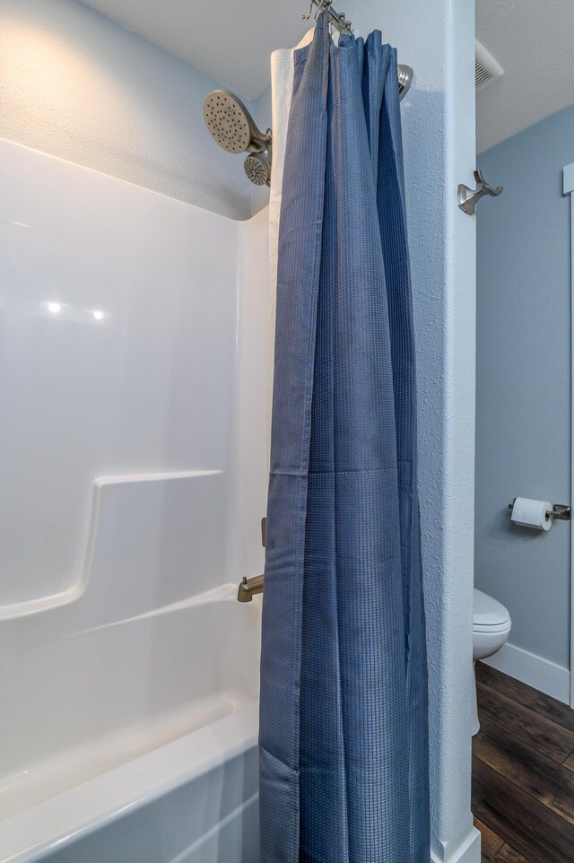 236 N Dade 147, Greenfield, MO 65661 - full bathroom featuring wood finished floors, toilet, shower / bath combo with shower curtain, and baseboards
