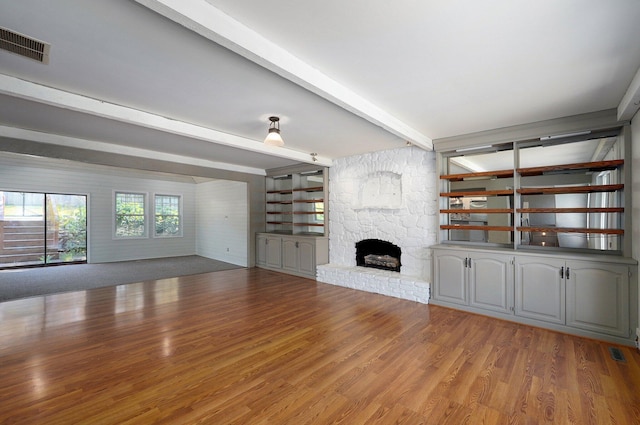 unfurnished living room with hardwood / wood-style floors, beam ceiling, and a fireplace