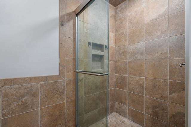 bathroom with an enclosed shower and tile walls