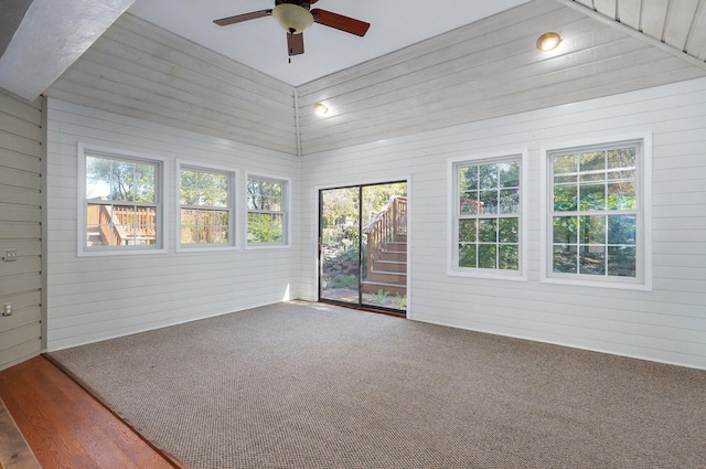 unfurnished room with hardwood / wood-style flooring, wood walls, and lofted ceiling