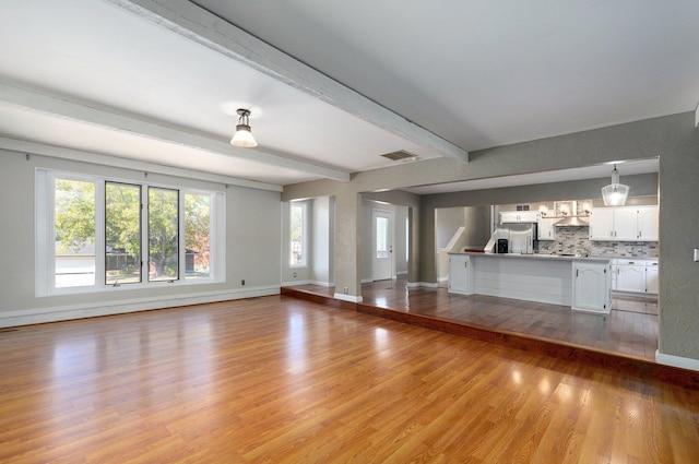 unfurnished living room featuring beam ceiling and light wood-type flooring