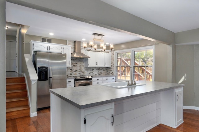 kitchen featuring white cabinetry, wall chimney range hood, stainless steel appliances, and a kitchen island with sink