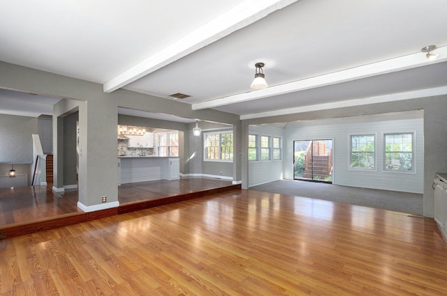 unfurnished living room featuring hardwood / wood-style flooring and beam ceiling