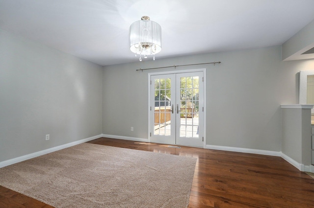 empty room with french doors, dark wood-type flooring, and a notable chandelier