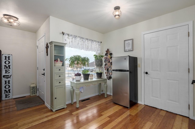 kitchen featuring green cabinets, light hardwood / wood-style floors, and stainless steel refrigerator