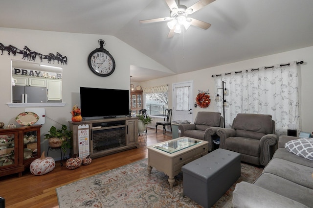 living room with ceiling fan with notable chandelier, wood-type flooring, and vaulted ceiling