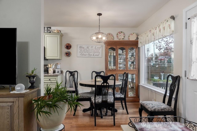 dining space with plenty of natural light, light hardwood / wood-style floors, and a notable chandelier