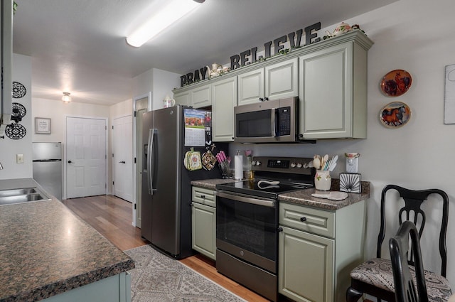 397 Micahs Xing, Reeds Spring, MO 65737 - kitchen featuring stainless steel appliances, a sink, dark countertops, and light wood-style floors