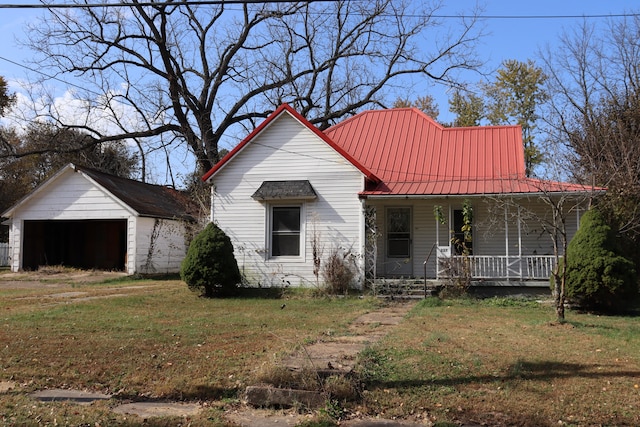 view of front of home featuring a porch, a garage, a front lawn, and an outdoor structure