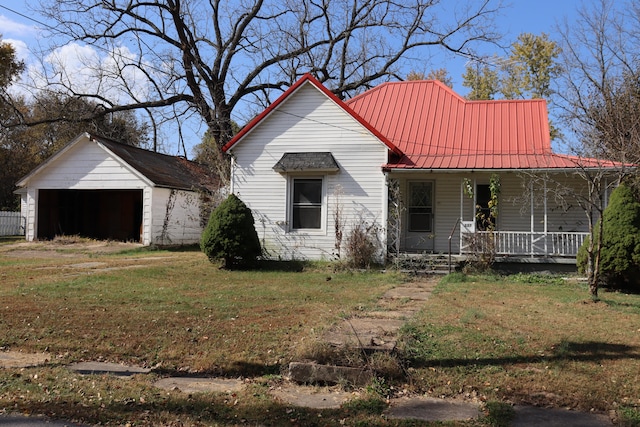 view of front facade with a garage, a front lawn, an outbuilding, and a porch