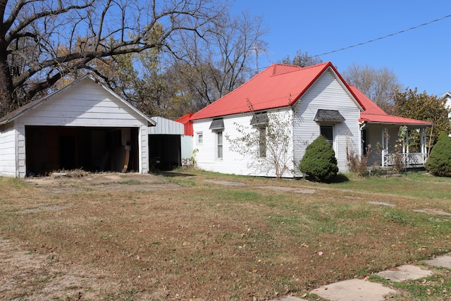 view of side of home featuring an outdoor structure, a garage, and a lawn