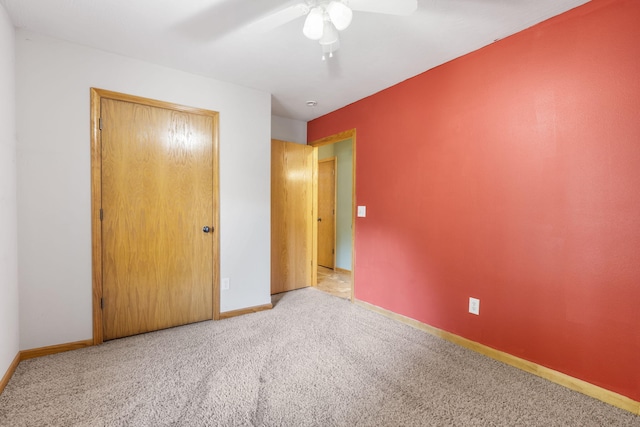 unfurnished bedroom with ceiling fan, a closet, and light colored carpet