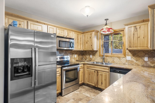 kitchen with hanging light fixtures, stainless steel appliances, light stone counters, backsplash, and sink