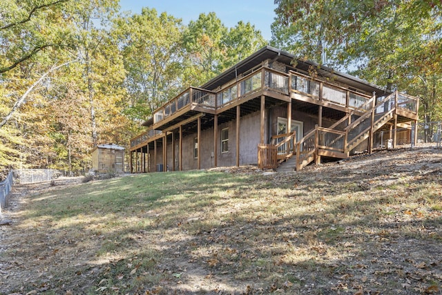 rear view of house featuring a wooden deck and a lawn