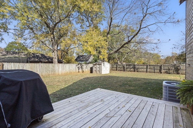 wooden deck featuring a storage shed, grilling area, a lawn, and central AC unit