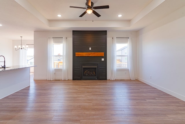 unfurnished living room with a large fireplace, light wood-type flooring, and plenty of natural light