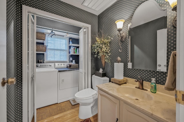 bathroom with vanity, toilet, parquet flooring, and separate washer and dryer