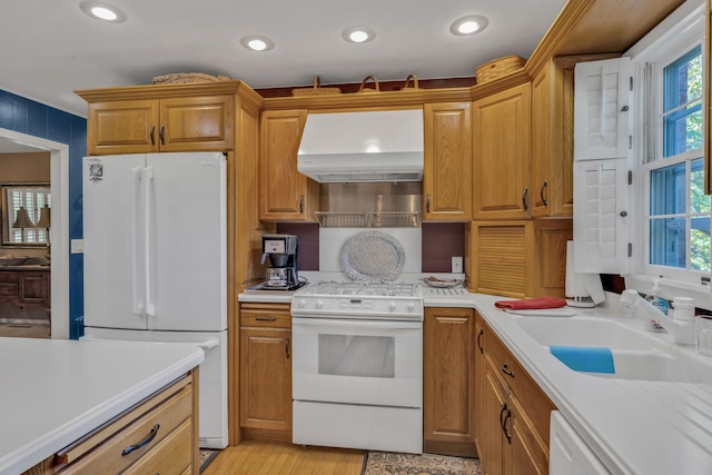 kitchen with white appliances, range hood, sink, and light hardwood / wood-style floors