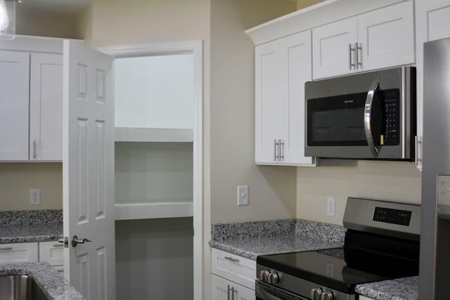 kitchen with appliances with stainless steel finishes, white cabinetry, and light stone countertops