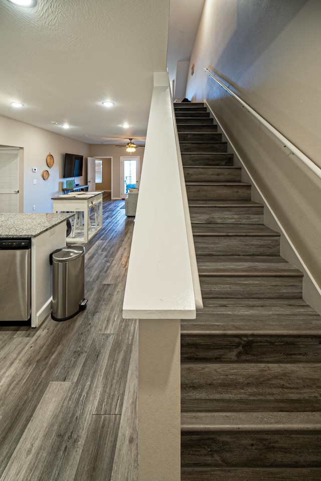 staircase featuring a textured ceiling, hardwood / wood-style flooring, and ceiling fan