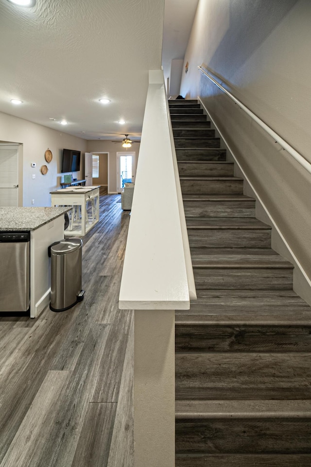 stairway featuring wood finished floors, ceiling fan, and recessed lighting