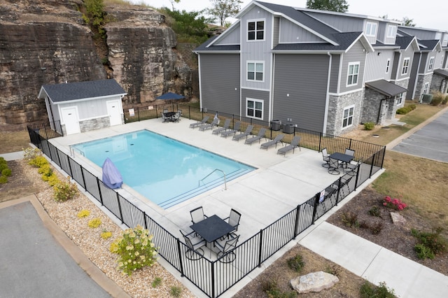 view of pool featuring an outdoor structure, a patio area, and central AC unit