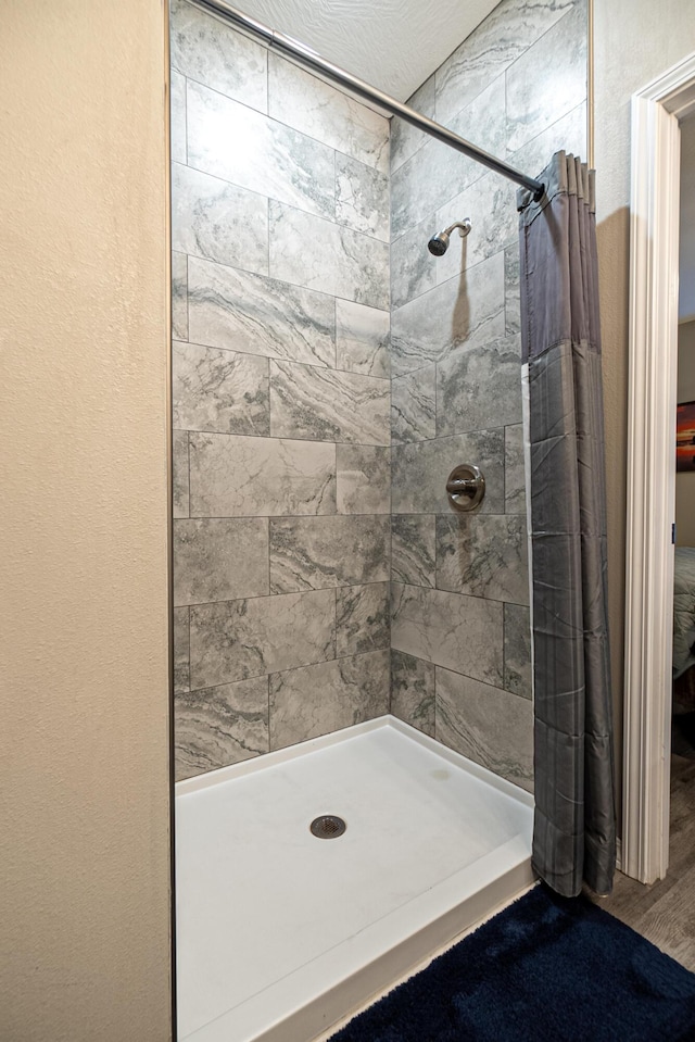 full bath featuring a tile shower and wood finished floors