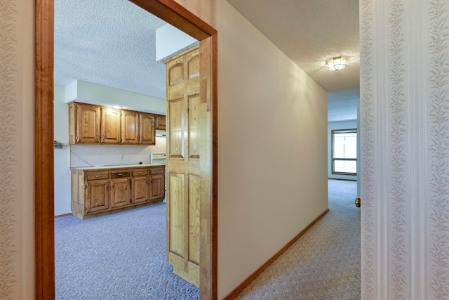 hallway with light carpet and a textured ceiling