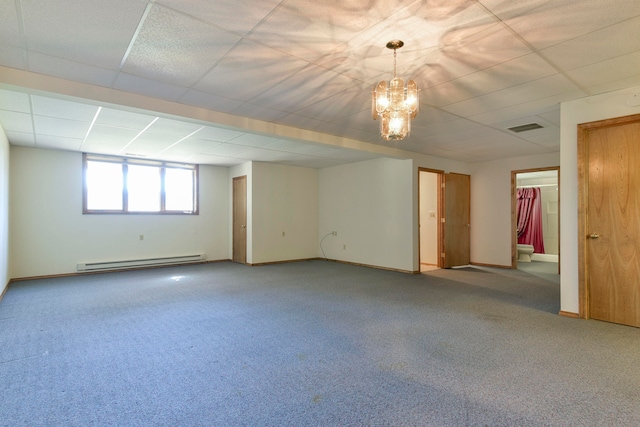 basement with a drop ceiling, baseboard heating, a chandelier, and carpet