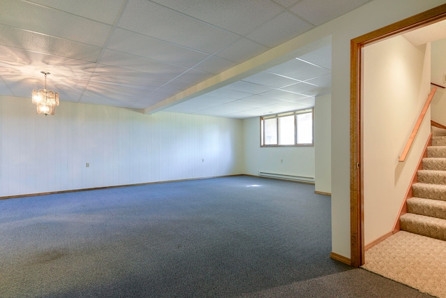 basement featuring an inviting chandelier, a drop ceiling, a baseboard heating unit, and carpet floors