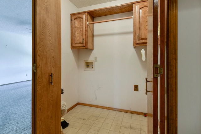 washroom with hookup for an electric dryer, hookup for a washing machine, a textured ceiling, and cabinets