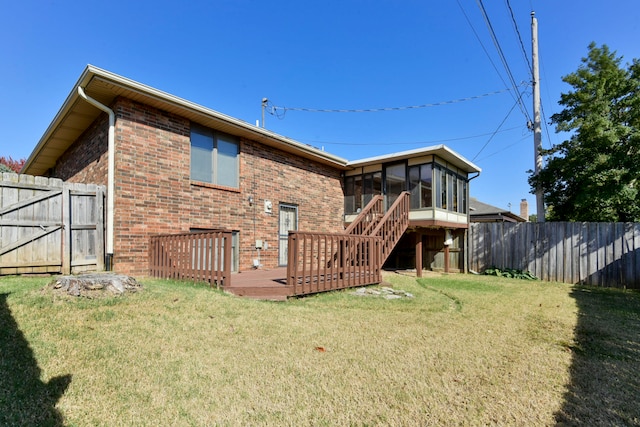 rear view of house with a wooden deck, a sunroom, and a lawn