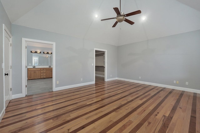 unfurnished bedroom featuring ensuite bathroom, a spacious closet, hardwood / wood-style floors, ceiling fan, and high vaulted ceiling