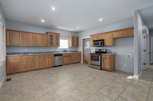 kitchen with stone countertops, stainless steel appliances, sink, and light tile patterned floors