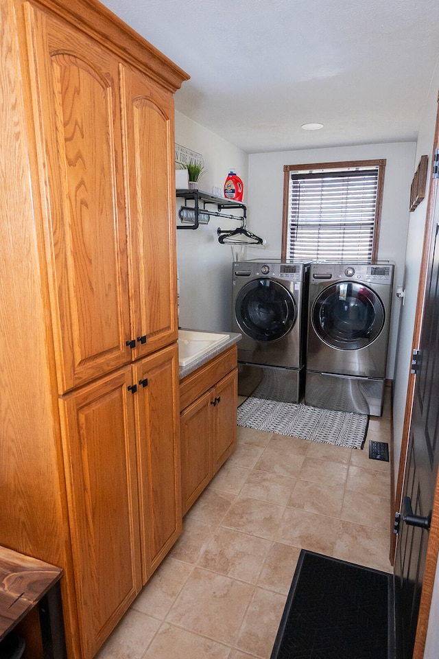 washroom featuring light tile patterned floors, washing machine and dryer, and cabinets