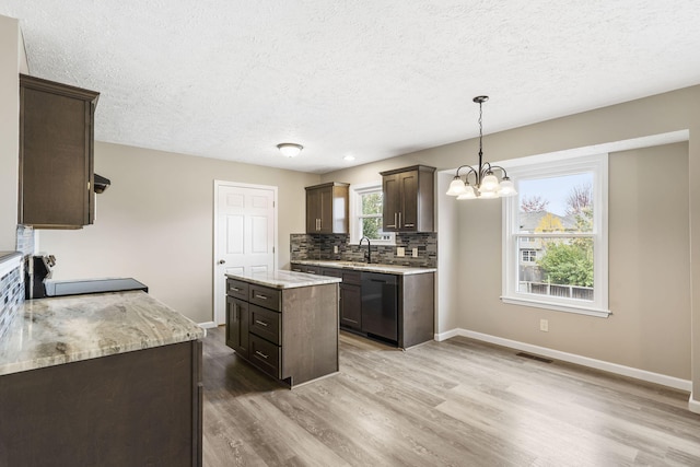 kitchen featuring dark brown cabinets, dishwasher, a sink, a notable chandelier, and a textured ceiling