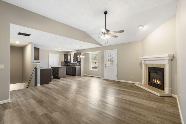 unfurnished living room featuring wood finished floors, a tiled fireplace, a ceiling fan, and baseboards