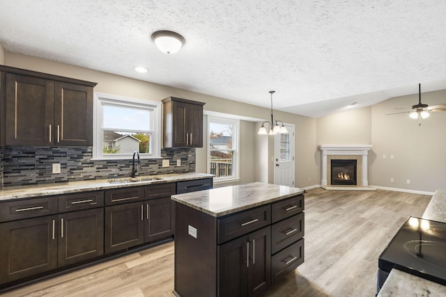 kitchen featuring a textured ceiling, backsplash, light wood-style flooring, and a sink