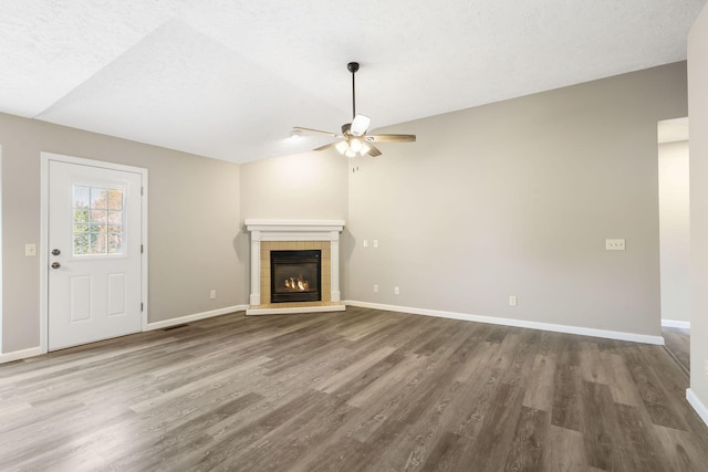 unfurnished living room featuring ceiling fan, baseboards, wood finished floors, and a fireplace