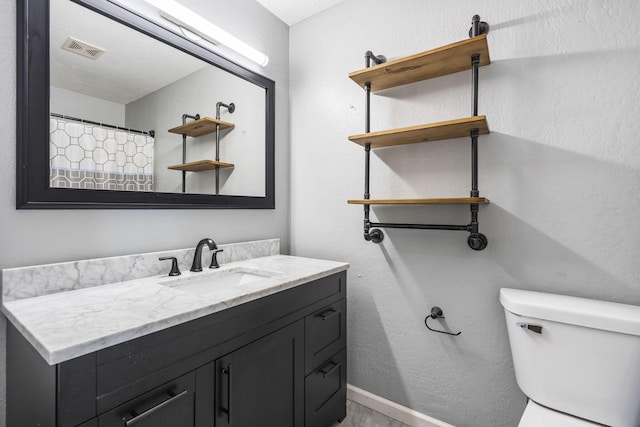 bathroom featuring toilet, walk in shower, and vanity