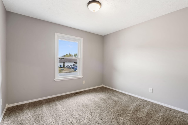 spare room featuring carpet, visible vents, and baseboards