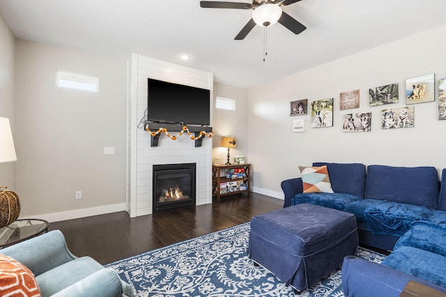 living room featuring dark wood-type flooring, ceiling fan, and a fireplace