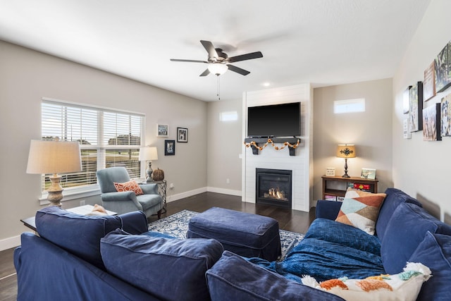 living room with dark wood-type flooring, a fireplace, and ceiling fan