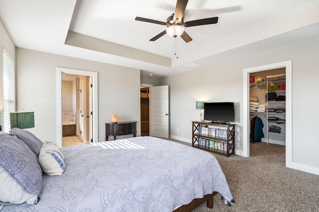 bedroom with a spacious closet, ensuite bath, a tray ceiling, ceiling fan, and light colored carpet