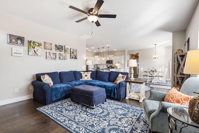 living room with dark wood-type flooring and ceiling fan with notable chandelier